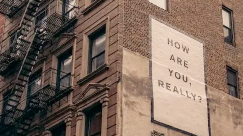 A brick building with a billboard that says, "how are you really?"