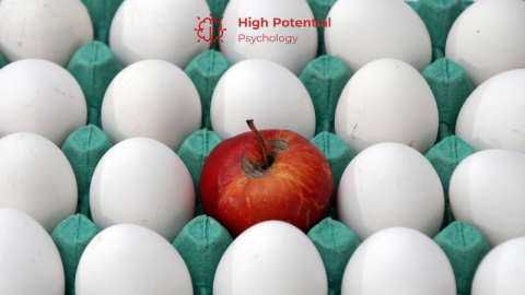 A bright red apple in a carton surrounded by white eggs